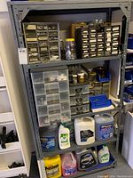 Full view of shelving unit with multiple organizers and containers of liquids on bottom shelf