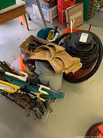 Red and black shop vacuum, tan leather tool belt, metal L-shaped brackets, and assorted clamps seen in an indoor setting.