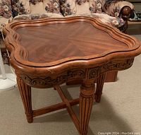 First table close-up showing carved apron and scalloped inlaid top with wood grain and recessed pattern