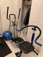 Photo showing elliptical machine, Ab-Sculpt machine, and blue Bosu ball in a tiled room corner.