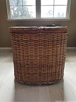 Front view of the large wicker laundry basket with closed hinged lids, showing natural woven texture.