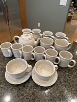 Full set of Longaberger vitrified pottery mugs, teapot, cups and saucers arranged on countertop.