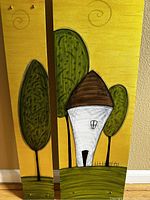 Front view of two vertically oriented metal art panels. Beige background with painting of a white house with brown roof and green trees with black outlines and swirled detail.