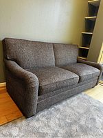 Angled left-side view of grey upholstery and curved arm