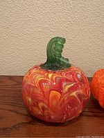 Close-up of red and yellow marbled pumpkin, showing swirl pattern, clear feet and green stem