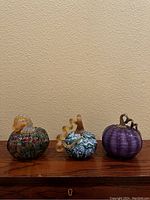 Three pumpkins displayed side by side on wooden surface