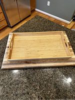Set showing large wooden cutting board with bamboo tray on top, photographed on kitchen counter.