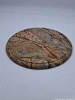 Full view of round marble trivet with natural vein patterns and smooth polished surface.