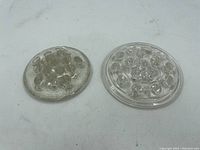Pair of oval vintage clear glass flower frogs with multiple circular holes for flower arranging, showing surface wear and age-related imperfections.
