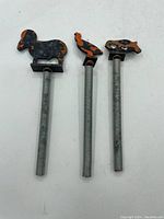 Three spring-mounted animal finials displayed upright: ram, bird, and pig shapes with visible paint wear and rust spots.