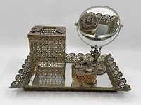 Overall set displayed on a mirrored tray showing tissue box holder, round mirror, and small covered box all with filigree metalwork.