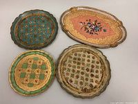 Top view of all four vintage Florentine serving trays illustrating various painted designs and patina wear