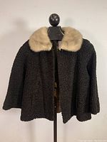 Front view of the black Persian lamb fur jacket with beige mink fur collar displayed on a mannequin.