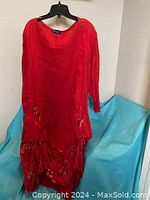 Front full view of the red boho dress hanging showing overall design, color, and floral print on bottom and pockets.