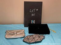 Photo of the three purses in the lot: black velvet purse with gold chain, silver clutch, and small geometric purse.