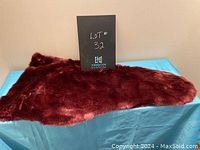 Red faux fur wrap laid flat on blue cloth surface, showing texture and size relative to flat surface