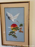 Framed Japanese embroidery picture showing flying egret with sun and pine trees.