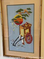 Full view of a professionally framed embroidered artwork showing a Japanese rickshaw on silk fabric with gold frame.