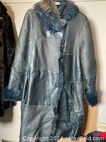 Front view of teal leather coat with faux fur collar and cuffs, showing patchwork leather design and snap closures.