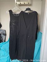 Mesh black sleeveless maxi dress and black maxi sweater coat hanging on hangers showing front details and overall shape.
