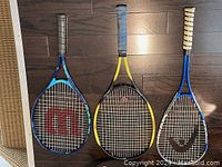 Three racquets side by side showing frames and strings.