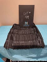 Black skirt folded, showing elastic waistband and metal tassel detailing.