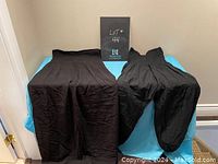 Set of two black garments: a maxi dress with tube top and wide leg pants with tube top, laid out flat to show full length and style.