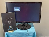 Samsung 23-inch LED monitor showing check signal cable message on screen with no input connected. Monitor stands on a circular base on a blue cloth surface.