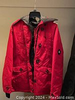 Front view of the red EKO women's winter jacket showing button closure, pockets, and hood.