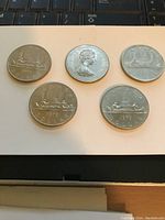Overview of five 1979 Canadian dollar coins placed on white background showing reverse side with canoe design.