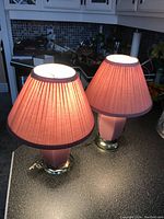 Two pink table lamps with pleated pink shades illuminated on kitchen counter