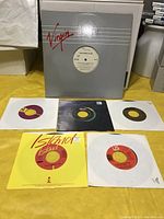 Six 45 rpm vinyl singles with various colored labels and paper sleeves, arranged in front of the Culture Club promotional record