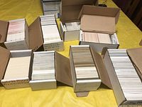 Top-down view of eight cardboard boxes filled with hockey cards, some boxes labeled with player names or dates but contents mixed.