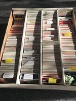 Photo of hockey cards sorted by player last names in divided cardboard box. Labels visible include Brian Leetch, John LeClair, Sylvain Lefebvre, and others. Cards packed tightly but appear well-preserved.