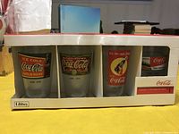 Set of four Coca Cola glasses in original Libbey packaging showing four different vintage designs.