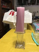 Photo showing the large pink rectangular candle placed on the clear glass candle holder from a frontal angle.