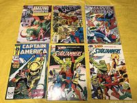 Photo showing all six Marvel comic books lying on a yellow tablecloth, titles visible.