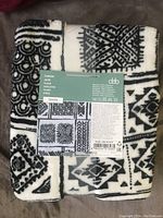 Folded throw blanket with visible Tanya label and black and white geometric patterns.
