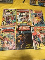 Overview photo showing all six comic books laid out on a yellow cloth.