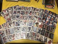 Several hockey card sleeves spread on a yellow surface showing a variety of player cards including red, white, and black background cards.