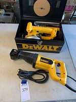 Overview of both power tools: DW303M reciprocating saw with power cord and DW930 cordless 136mm trim saw inside metal carrying case, with charger visible inside.