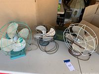 Photo of all three vintage fans arranged on a table showing size and general condition.