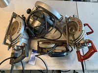Overview of four electric saws on table showing SkilSaw worm drive and circular saws plus Rockwell trim saw.