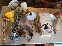 Overhead photo featuring all 8 retro desk lamps in various colors including yellow, white, red, beige, and metallic finishes. Some cords are visible and the lamps display wear and need cleaning.
