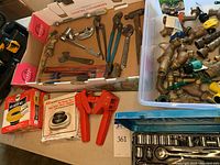 Overview of plumbing wrenches, faucet attachments, boxes of wax toilet gaskets, and part of the drive socket set