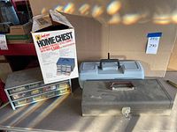 Three storage units including a HomeChest 15 drawer steel portable cabinet in box, metal organizer with 12 small drawers, and a black metal toolbox.