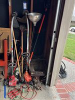 Full view of assortment of garden tools including gas string trimmers, long-handled tools, vintage sprinklers, and other miscellaneous tools.