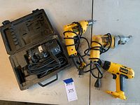 Photo showing the Craftsman laminate trimmer in its black hard carrying case alongside three yellow Dewalt electric tools with cords.