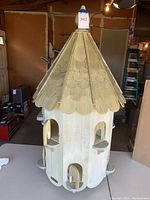 Front and exterior view of the large multi-level birdhouse showing scalloped shingle roof and multiple door openings.