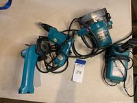 Three Makita power tools laid on a table with cords visible, including a circular saw and screwdriver.